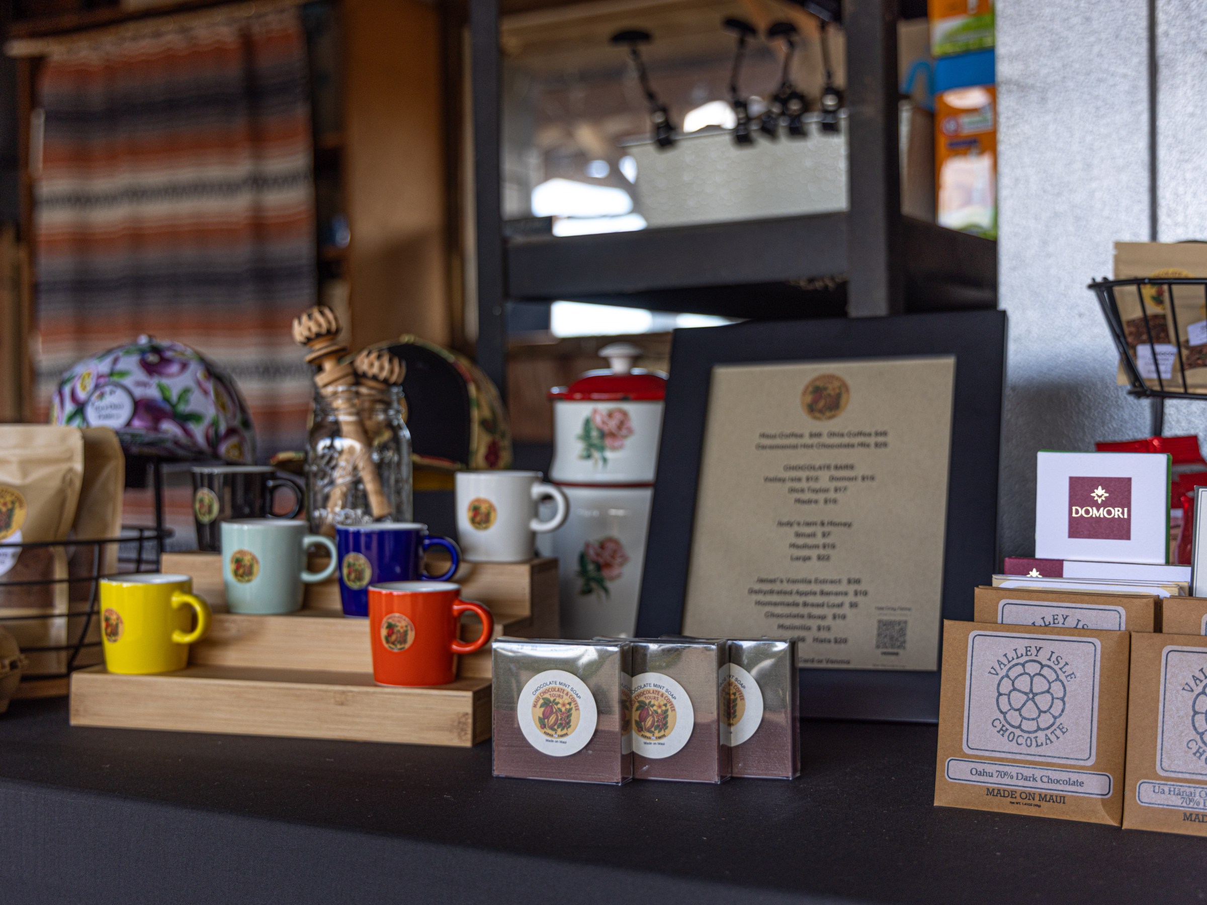 Colorful mugs, menu, and chocolate bars displayed on a table in a shop.