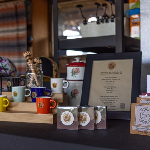 Colorful mugs, menu, and chocolate bars displayed on a table in a shop.