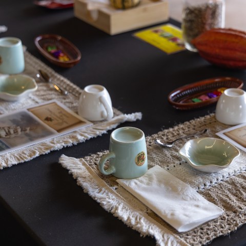 Table set with placemats, cups, saucers, and booklets for a chocolate tasting.
