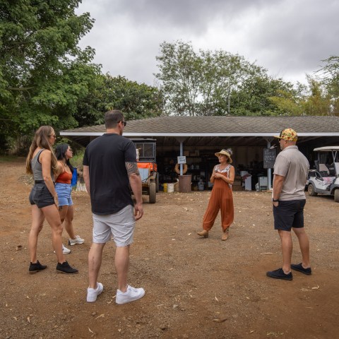 Group of people standing outdoors near a garage with trees in the background.