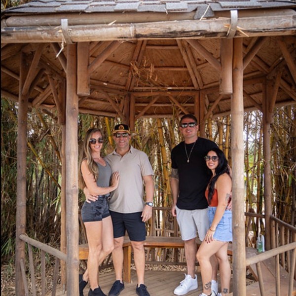 Four people standing in a wooden gazebo surrounded by bamboo.